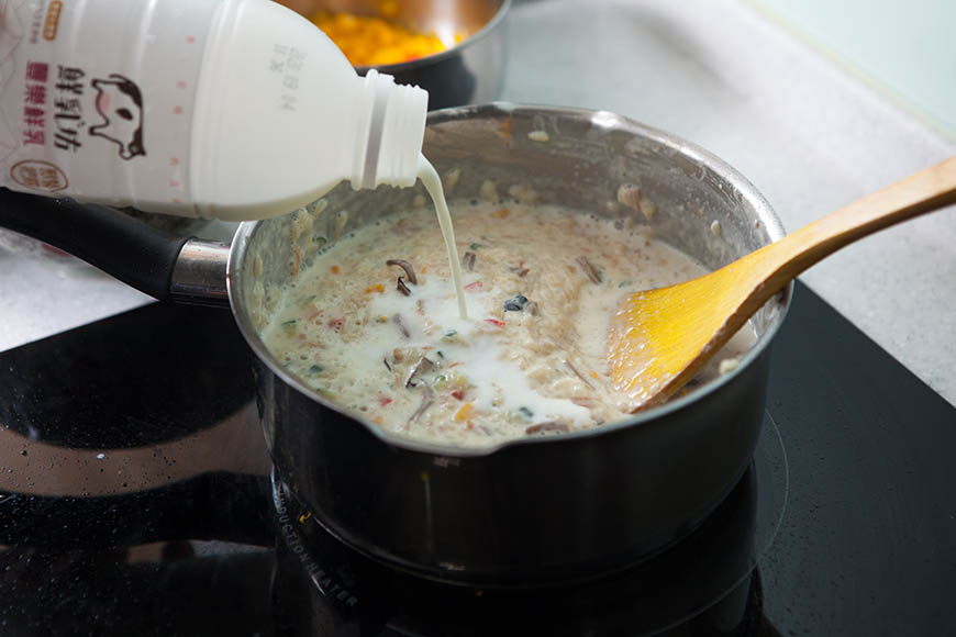 鮮奶燉飯料理步驟，將剩餘鮮奶、高湯分次加入慢慢拌炒。