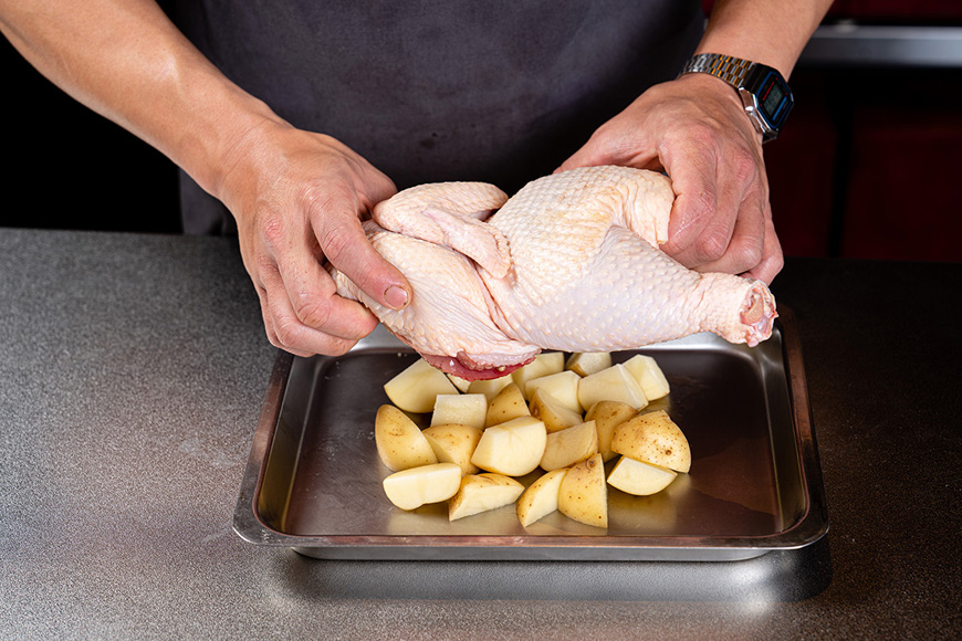 將馬鈴薯切塊，放上半雞，烤箱預熱。
